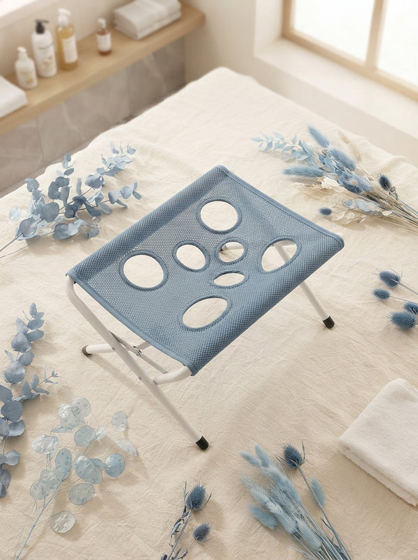 A pet grooming hammock laid out on a cream linen surface with soft blue decorative accents, styled for a premium pet care bra